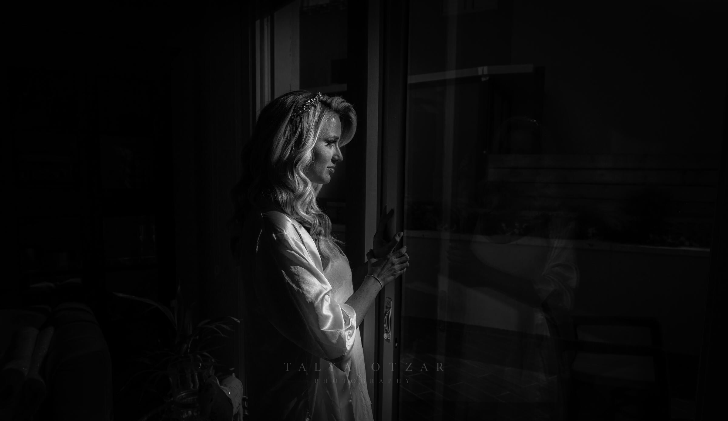 The bride at the window in her robe on the morning of the wedding