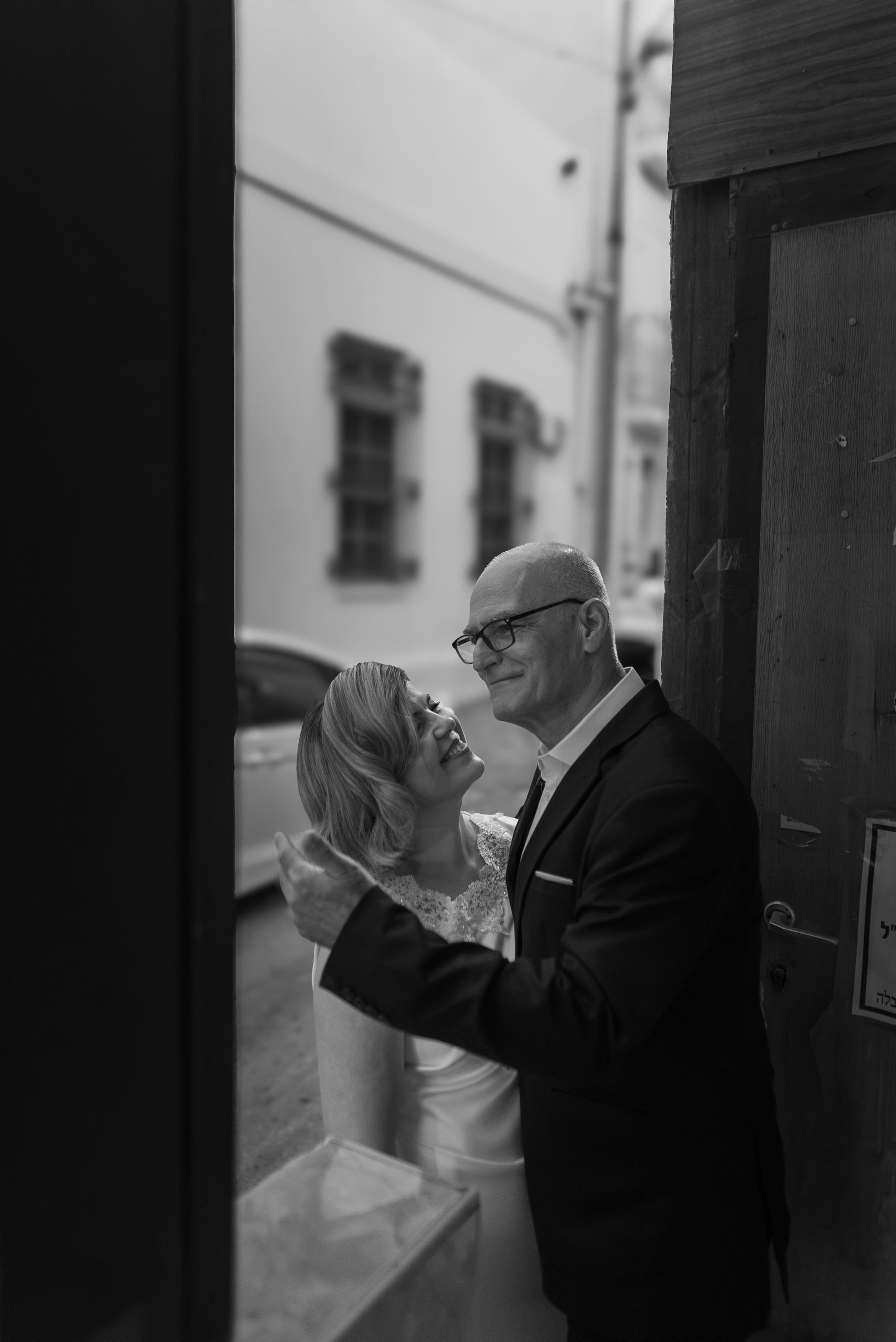 The bride and groom looking at each other in a doorway, black and white