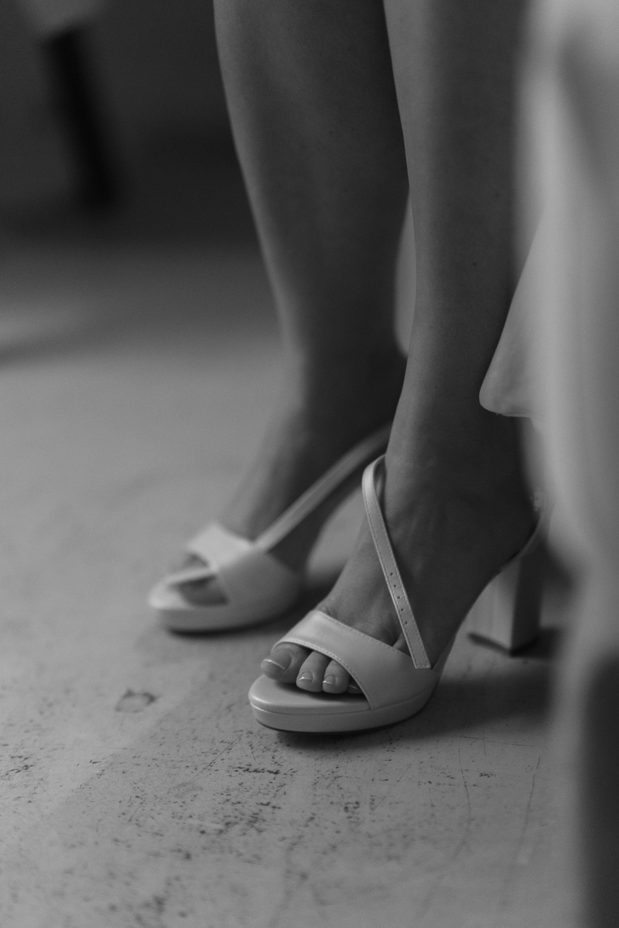 The bride's feet in white heeled sandals, black and white