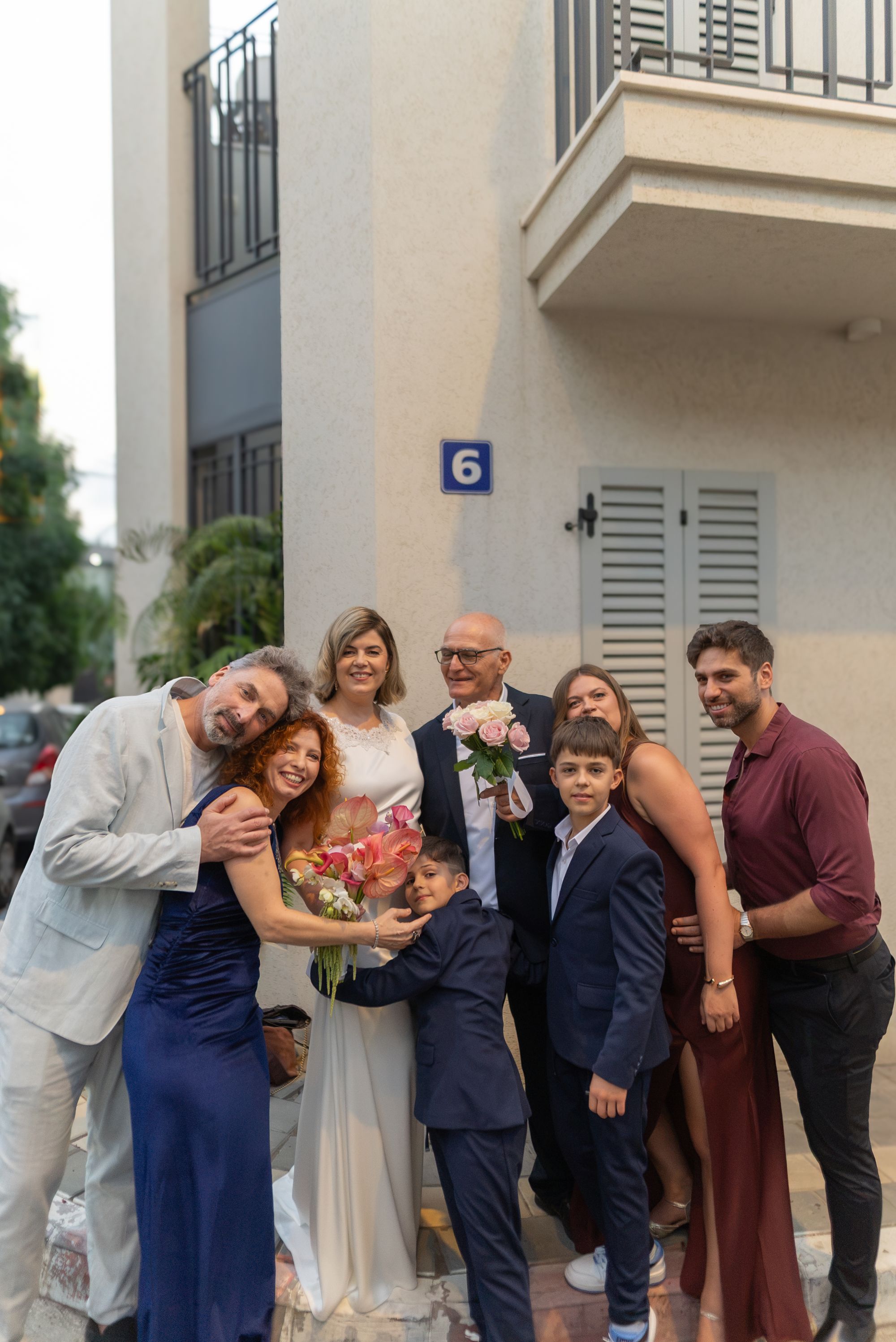 The couple and their family hugging together outside the building