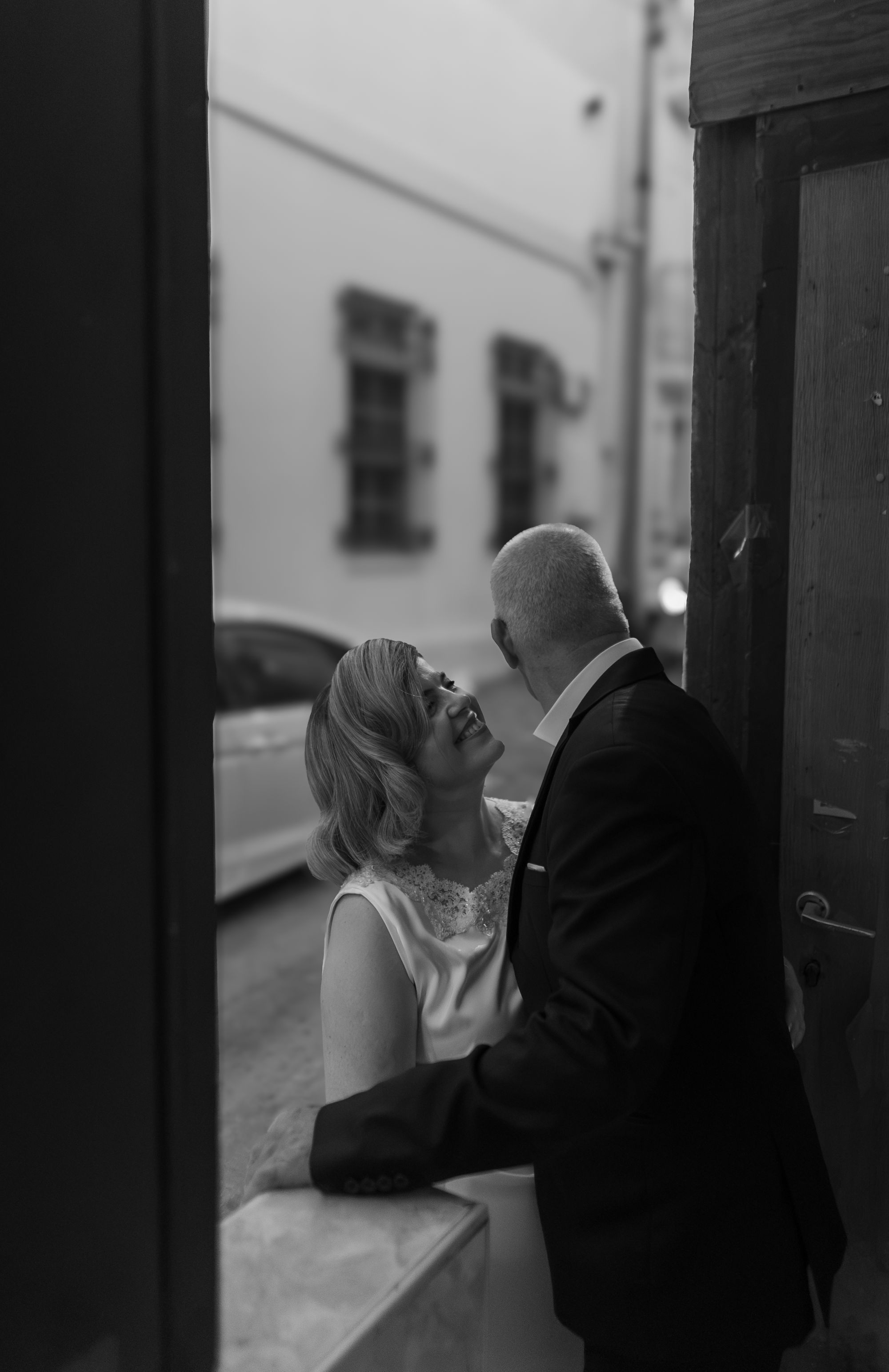 The bride smiling up at the groom in a doorway, black and white