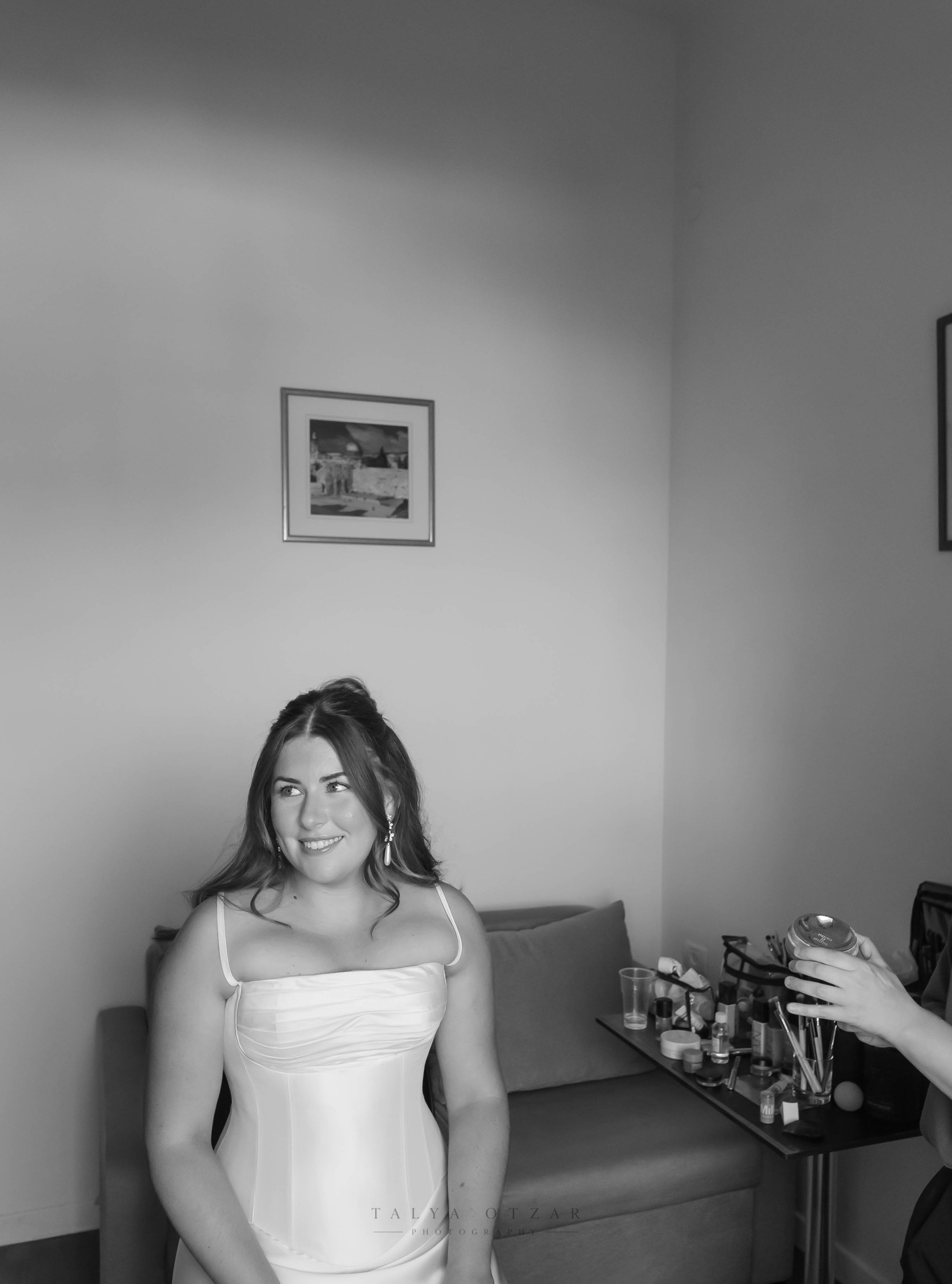 The bride in her dress, smiling toward the window, black and white