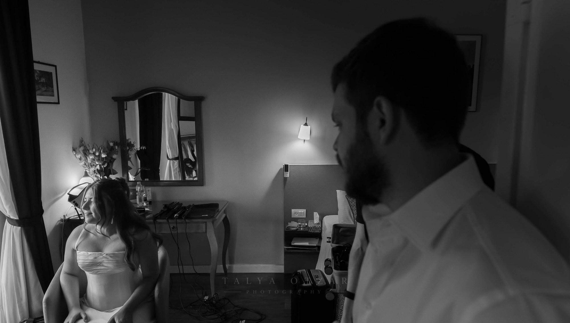 The groom looking at the bride across the room, black and white