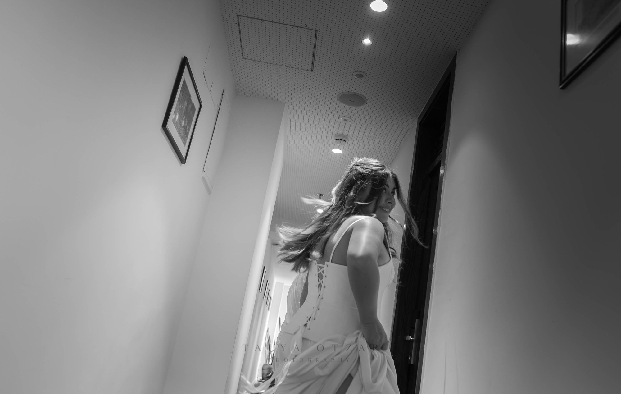 The bride hurrying down the hallway, her dress in motion, black and white
