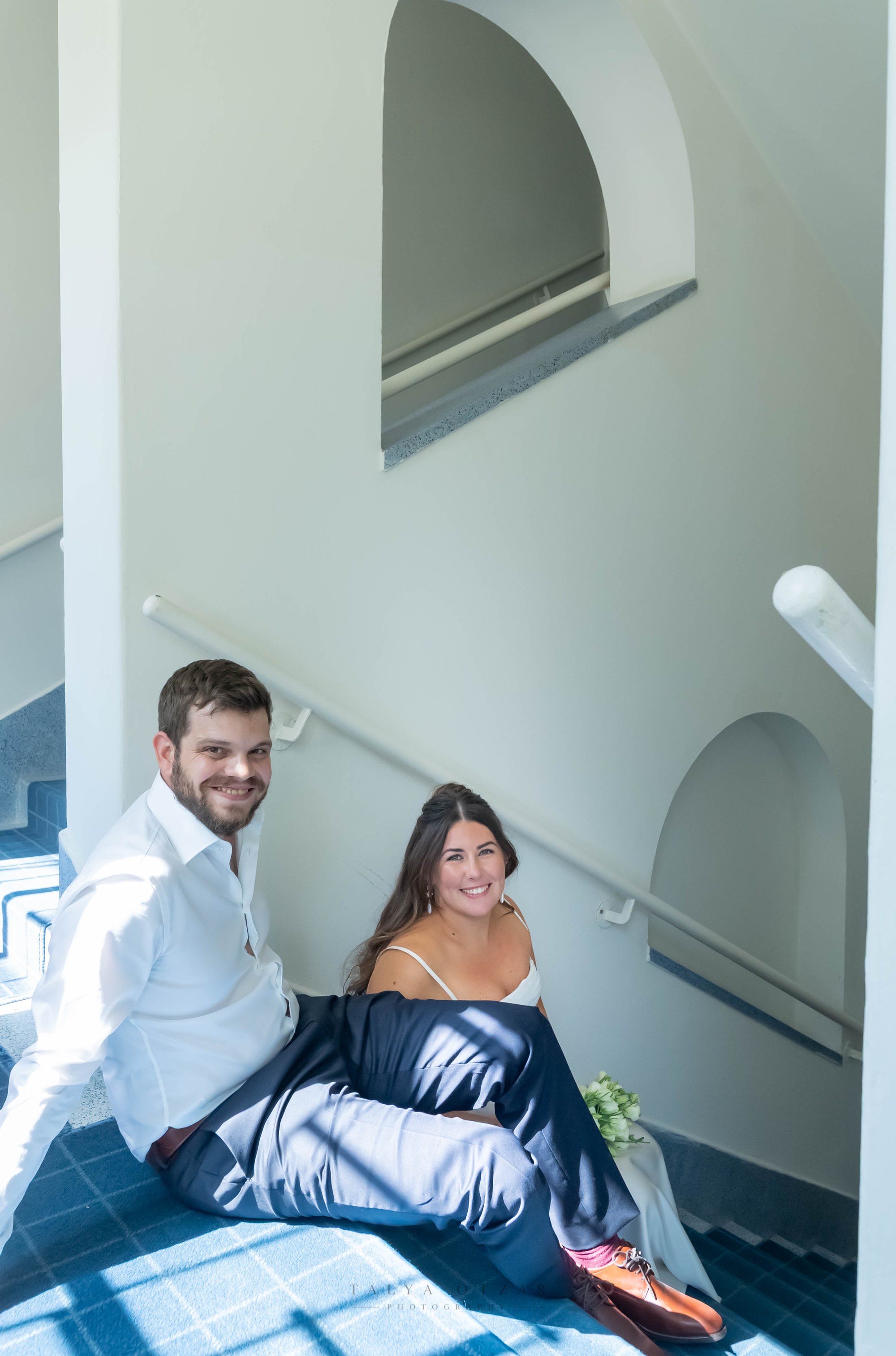 The couple sitting on the blue-tiled stairs, smiling at the camera