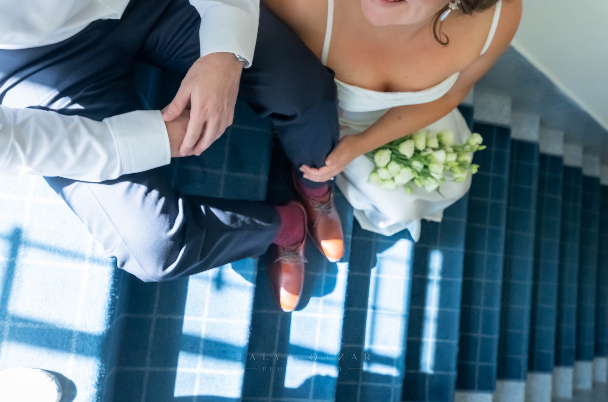 The couple's feet on the blue stairs seen from above, the bouquet on her lap