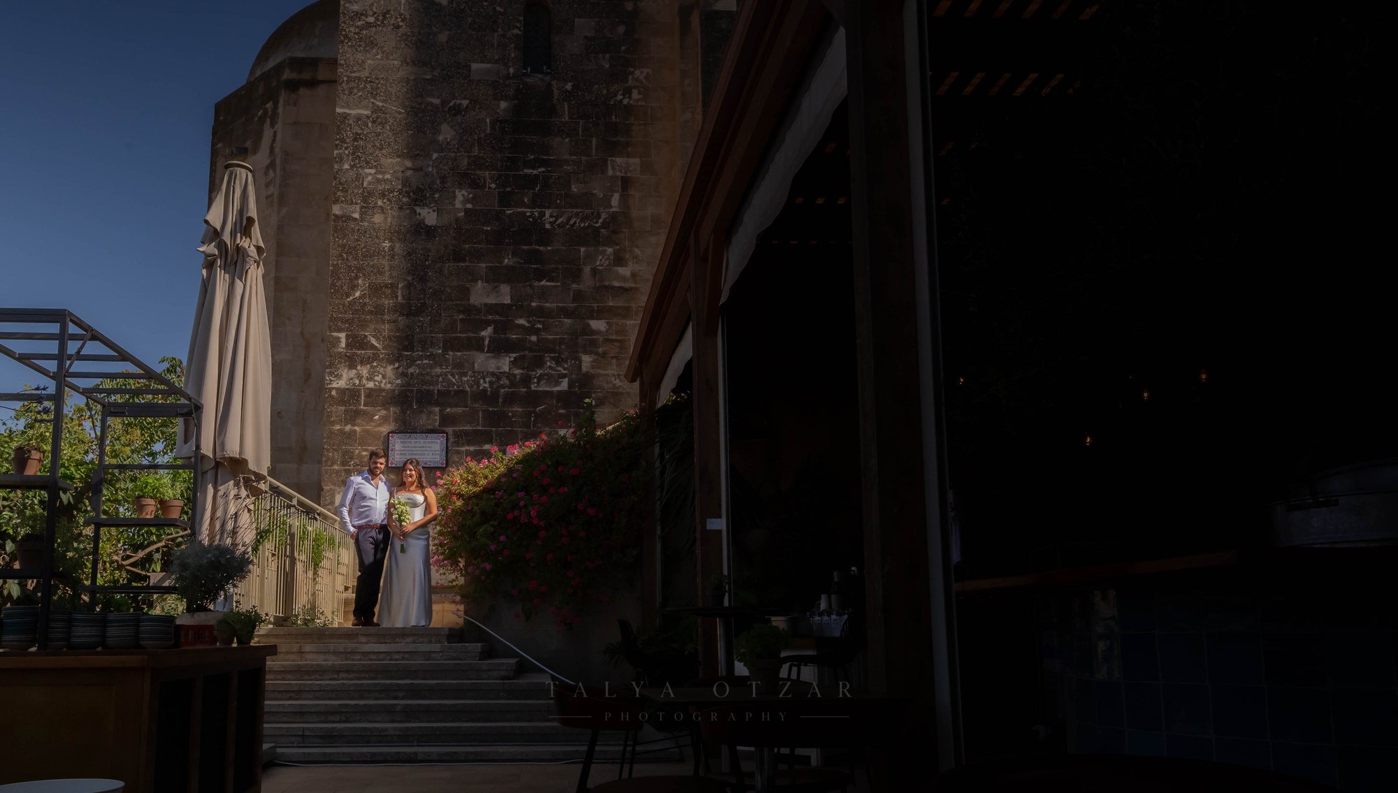 The couple at the top of the stone steps outside the old building, in deep shadow