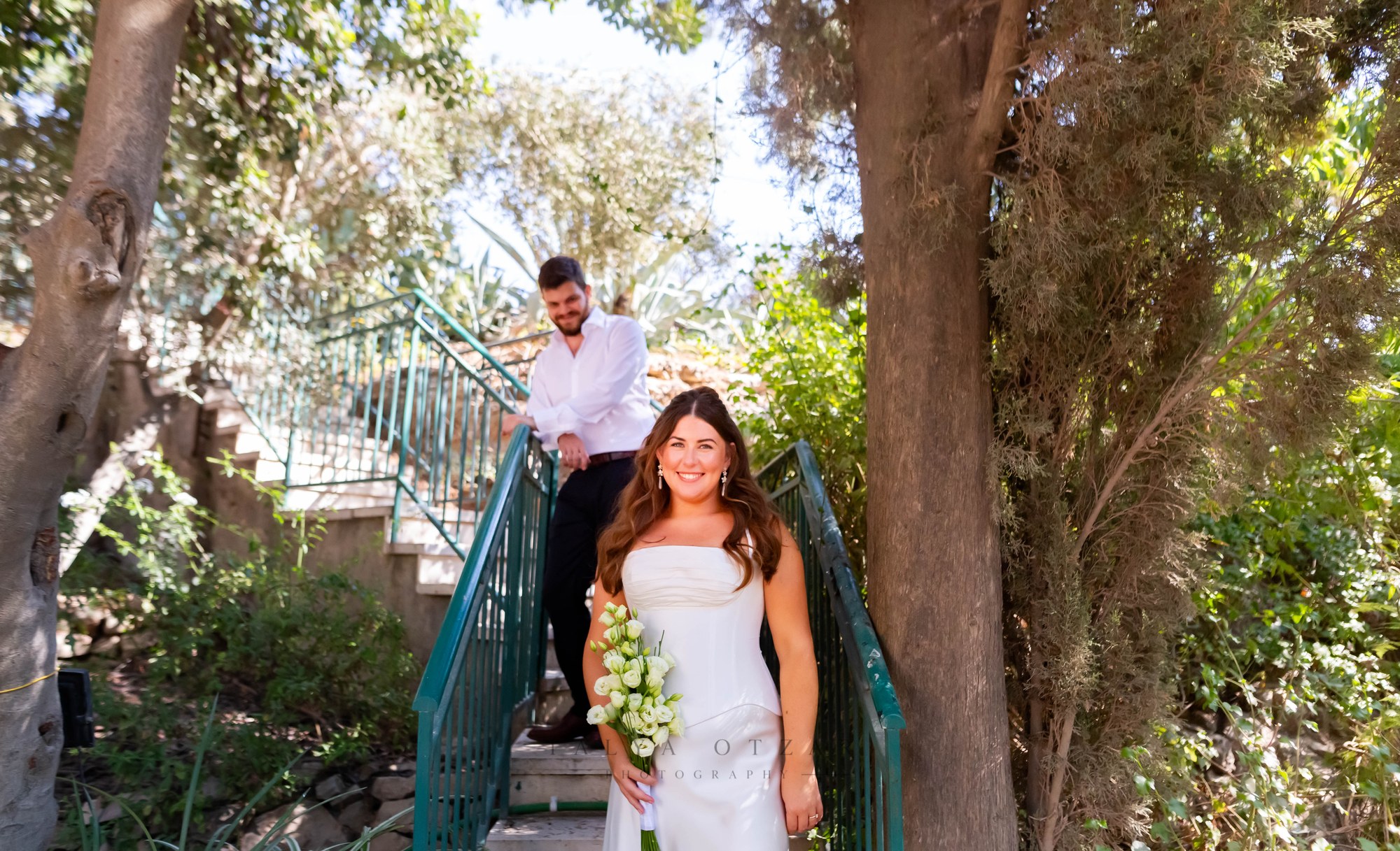 The couple coming down the garden stairs between the trees
