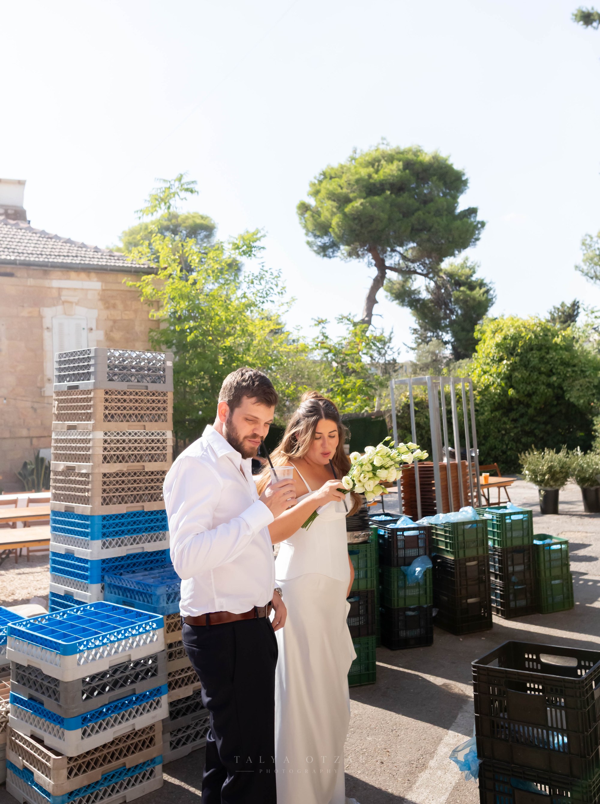 The couple sharing a drink among stacked crates behind the venue