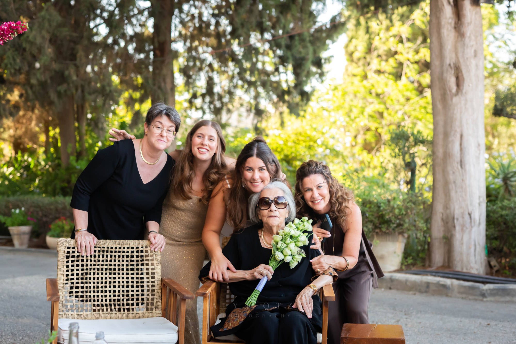 Women of the family gathered around an elderly woman holding the bouquet in the garden