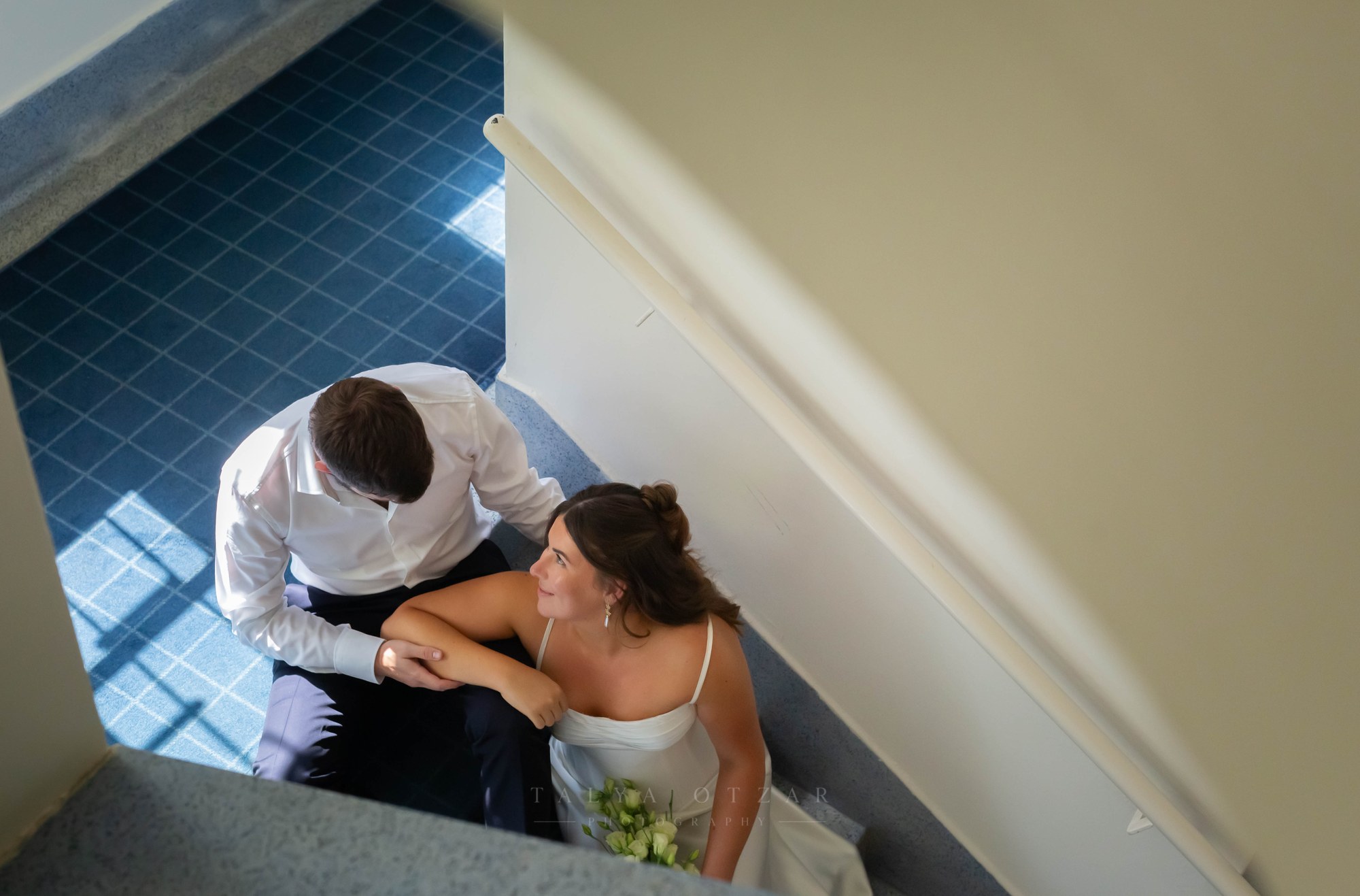 The couple sitting together on blue-tiled stairs, seen from directly above