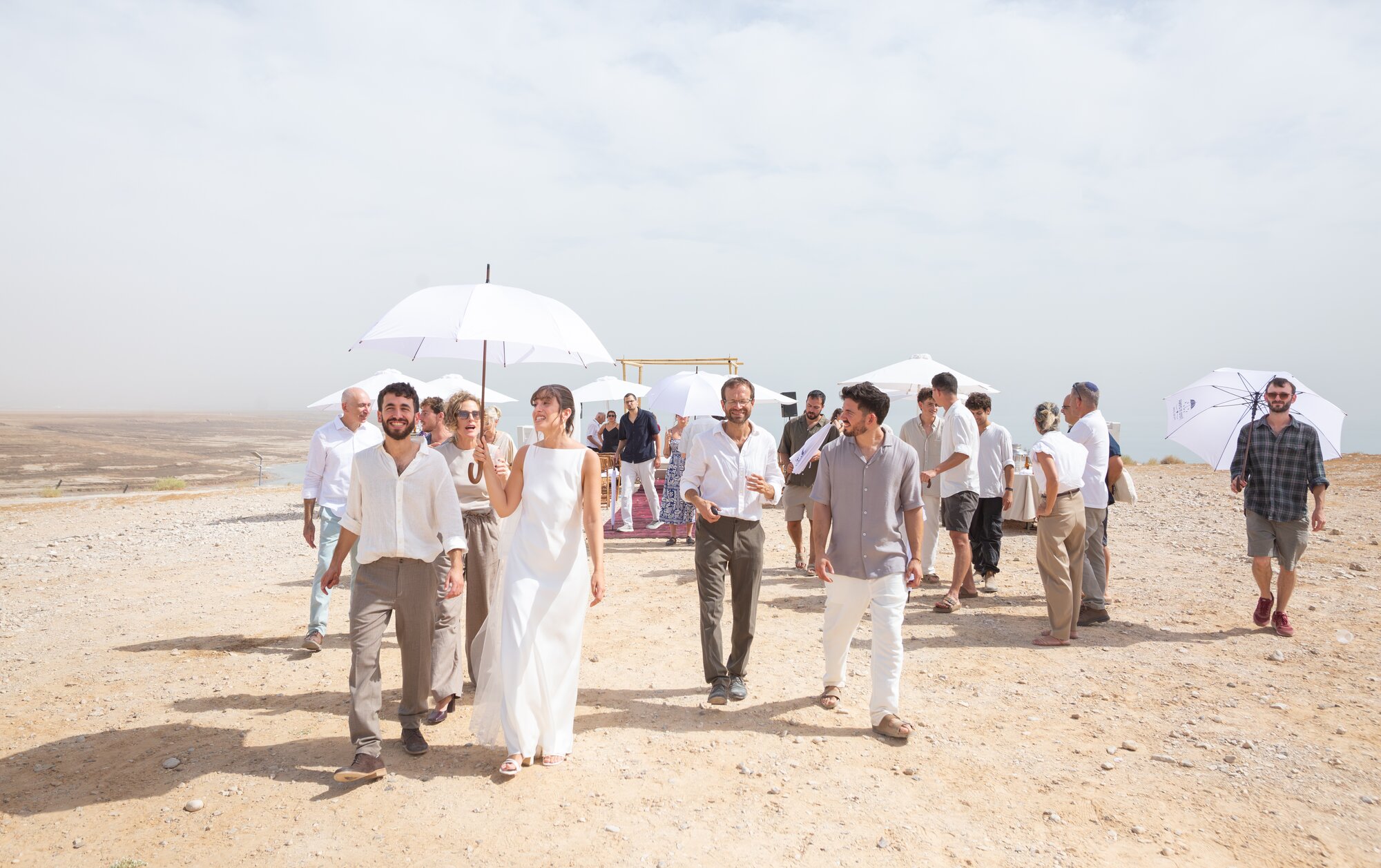 The wedding party walking along a desert track toward the sea