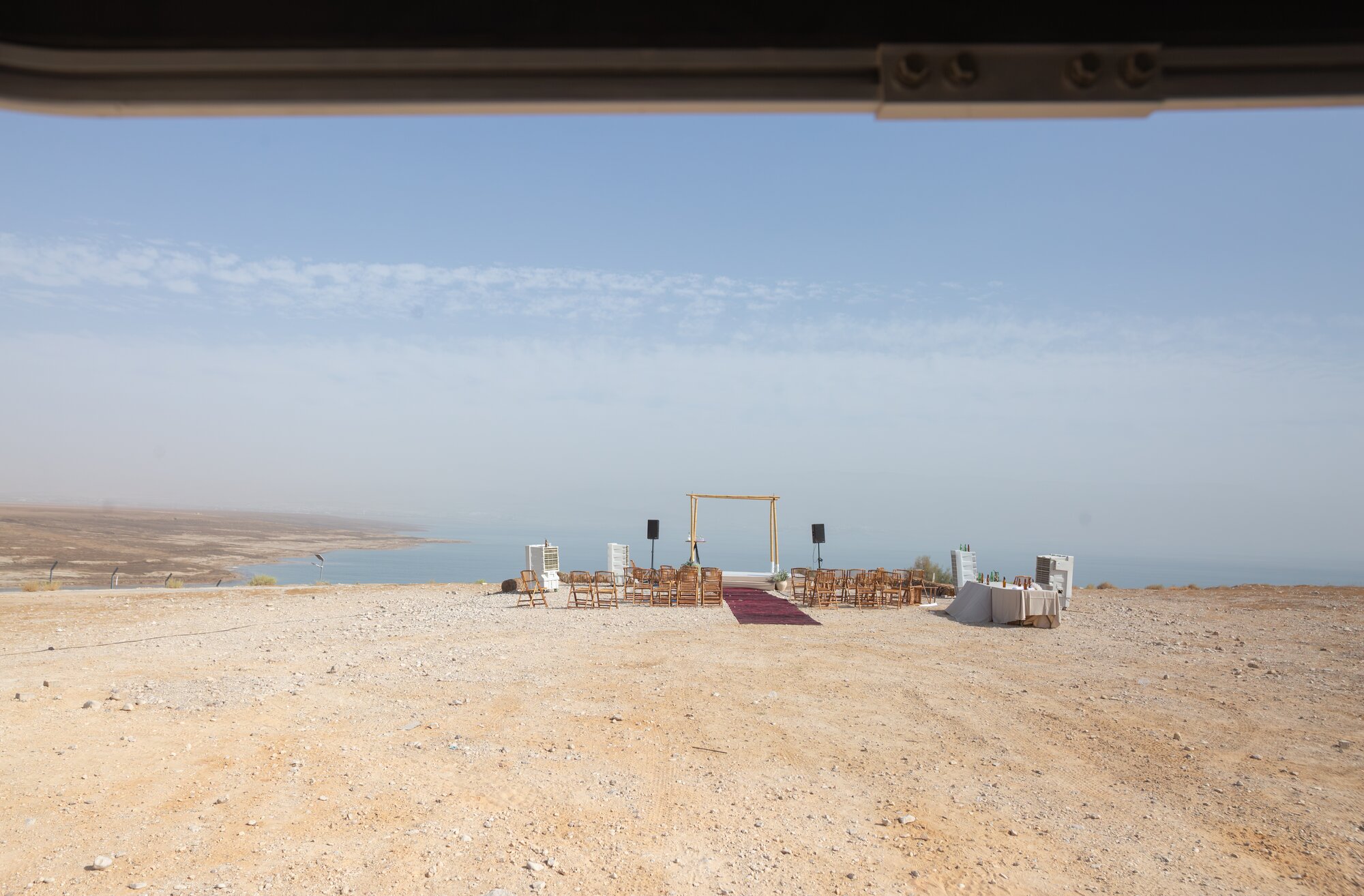 The ceremony set up on a desert ridge above the Dead Sea, seen through a vehicle window