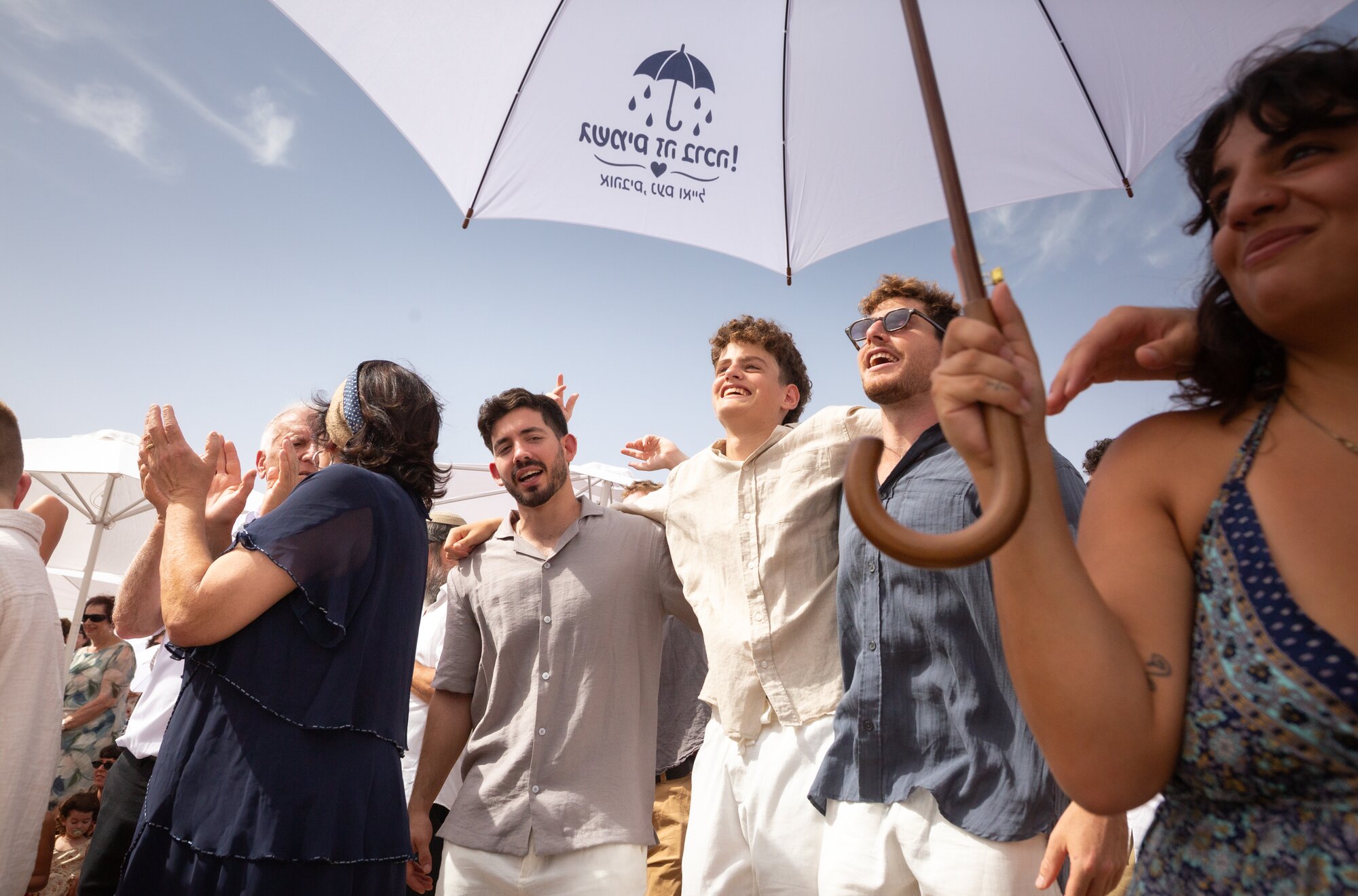 Friends singing and laughing under a white umbrella