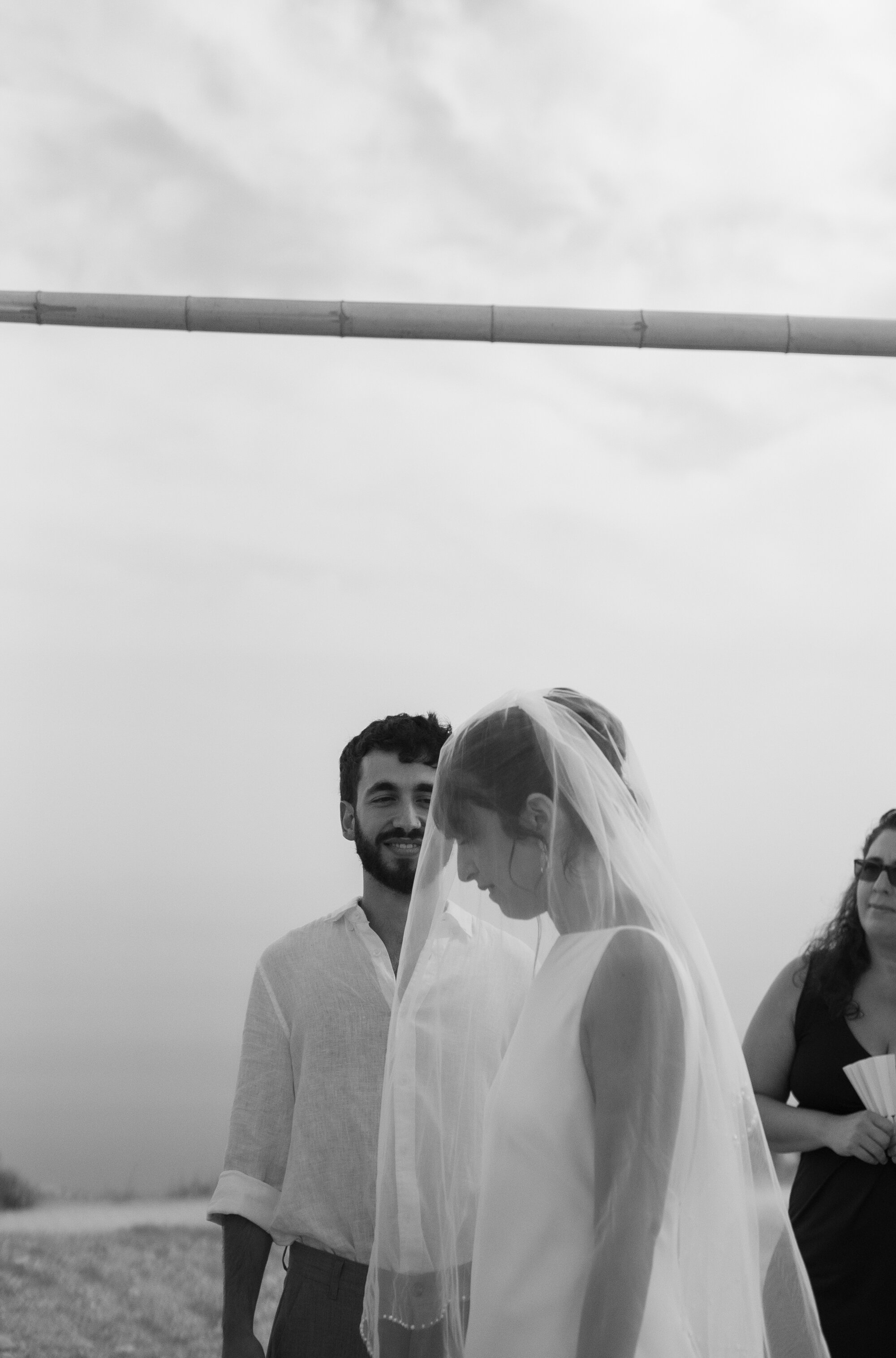 The bride turning toward the groom under the chuppah, black and white