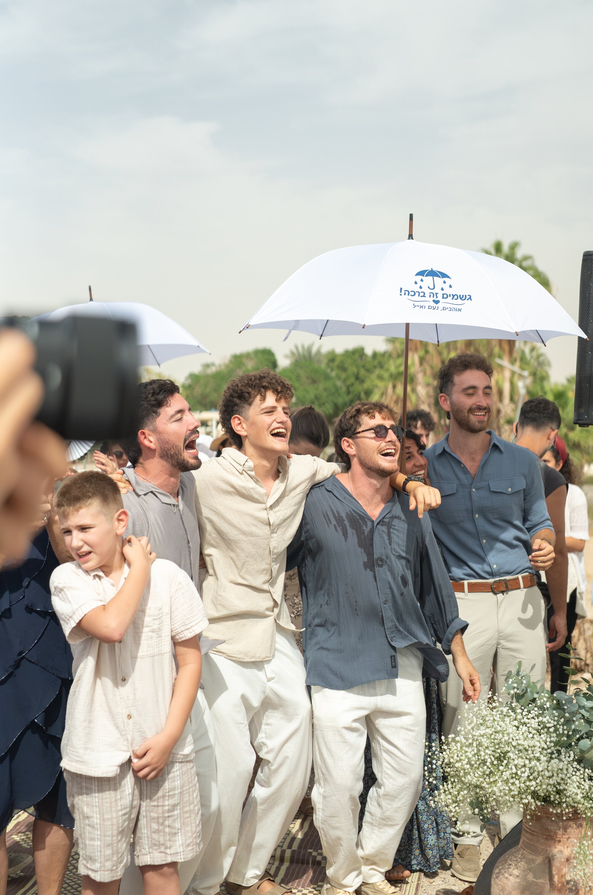 Friends laughing and cheering beneath white umbrellas