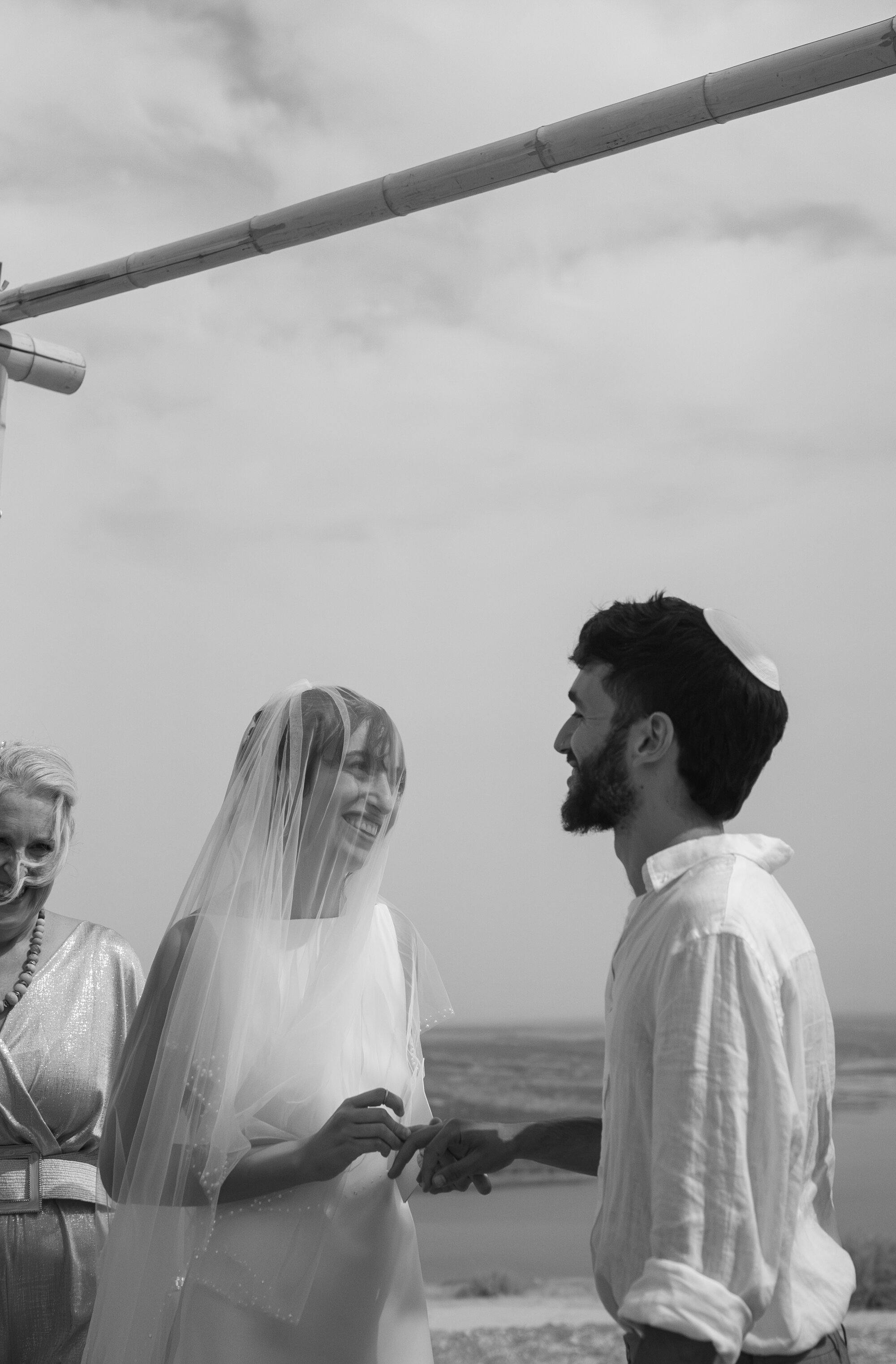 The bride and groom exchanging rings under the chuppah, black and white