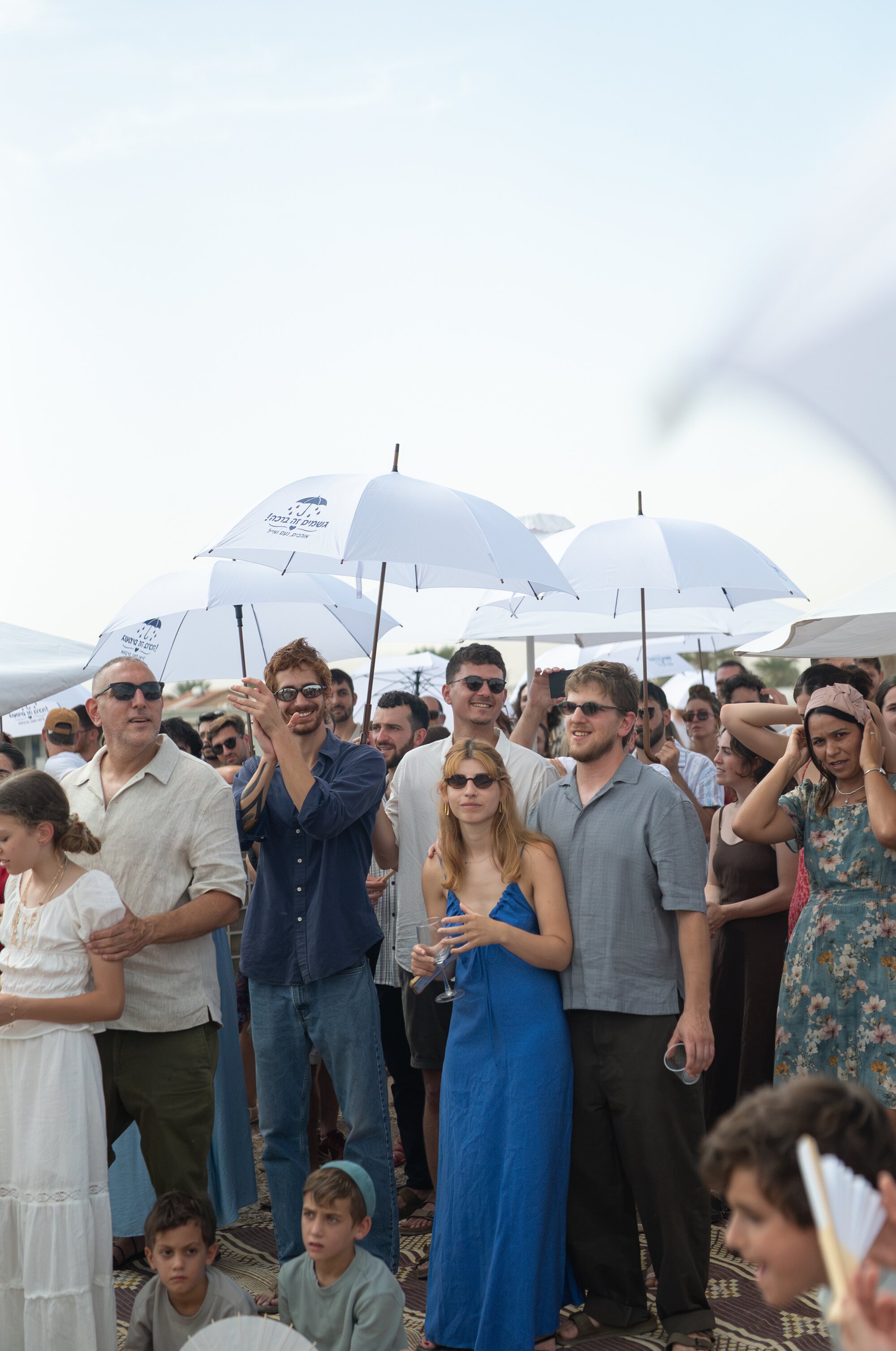 Guests applauding beneath white umbrellas