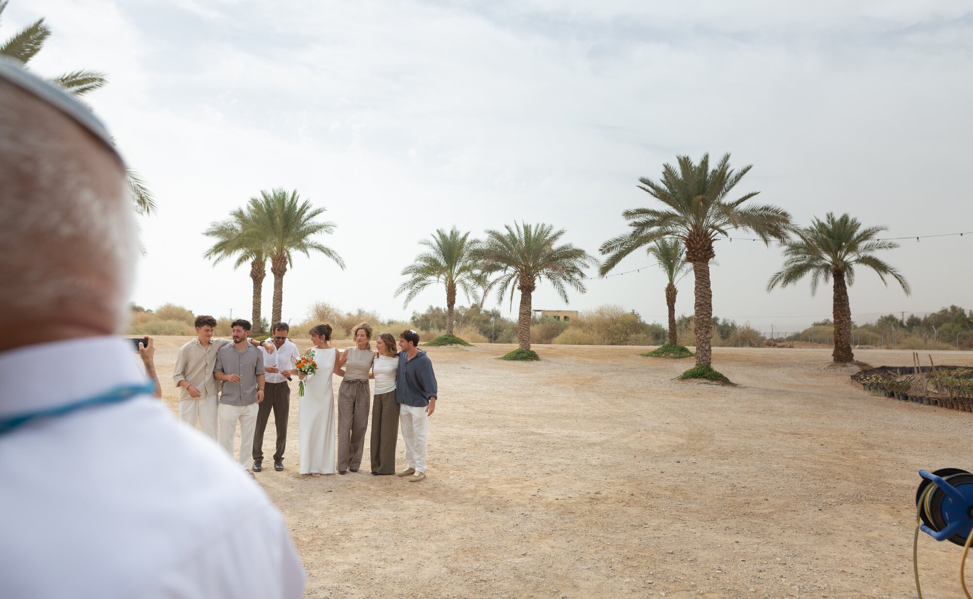 Family and friends gathered for a portrait among the palm trees before the ceremony